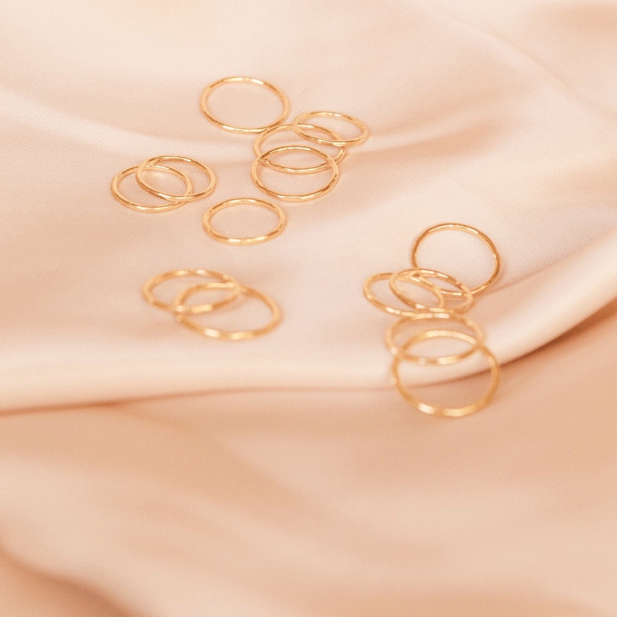 Rings on pink satin, stacking Hammered Band Rings, made in America by Katie Dean Jewelry