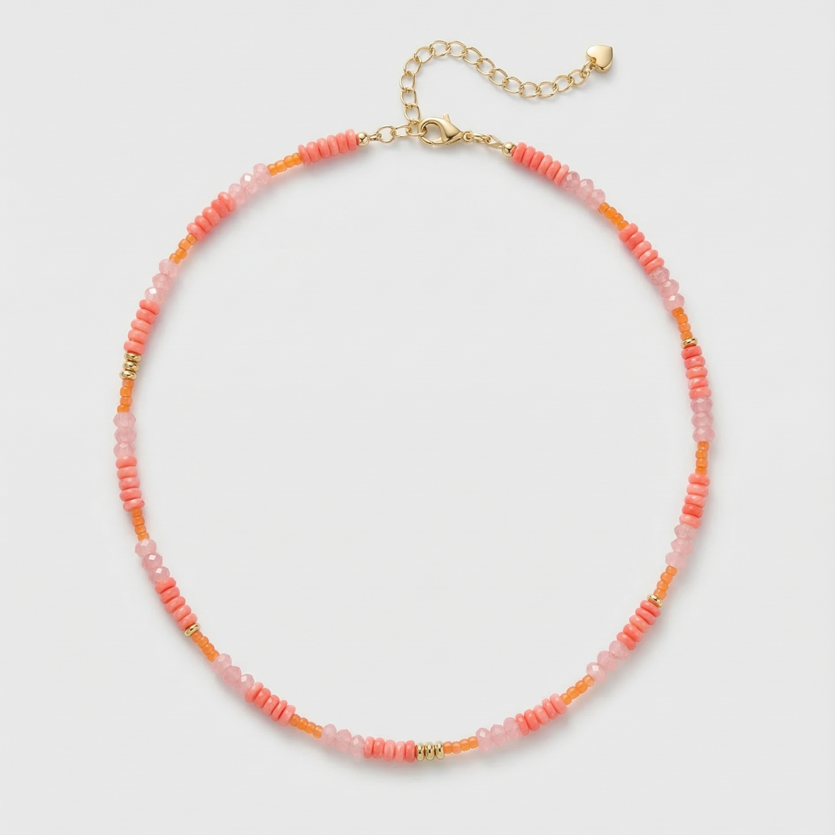 Coral and pink beaded gemstone necklace with gold accents and gold extension chain on a light gray background