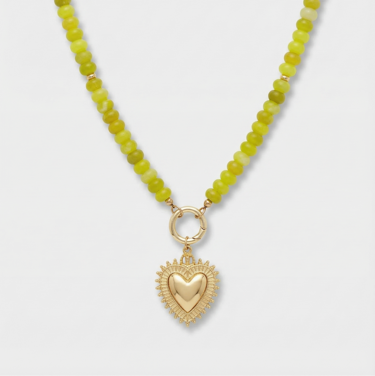 Necklace with green beads and a gold heart pendant on a white background