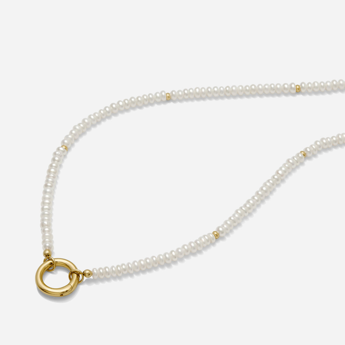 Pearl necklace with a gold circle pendant on a white background handmade by Katie Dean Jewelry.