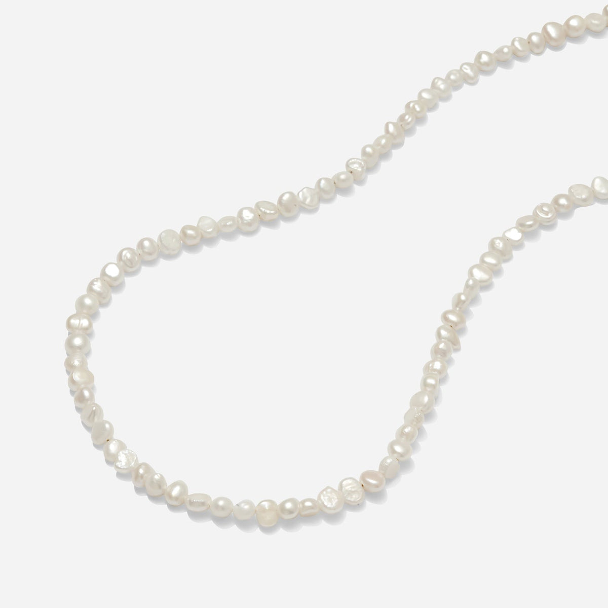 Flat organic freshwater pearl necklace with gold fill clasp hand beaded by Katie Dean Jewelry on a light grey background.