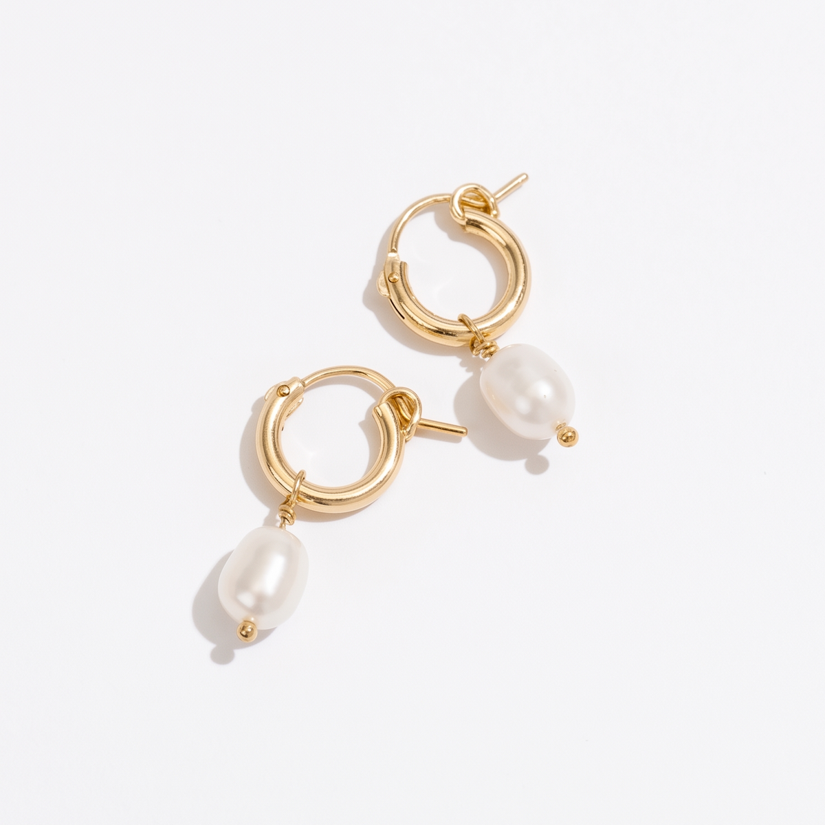 A pair of gold hoop earrings with dangling baroque pearl beads, photographed on a clean white background.