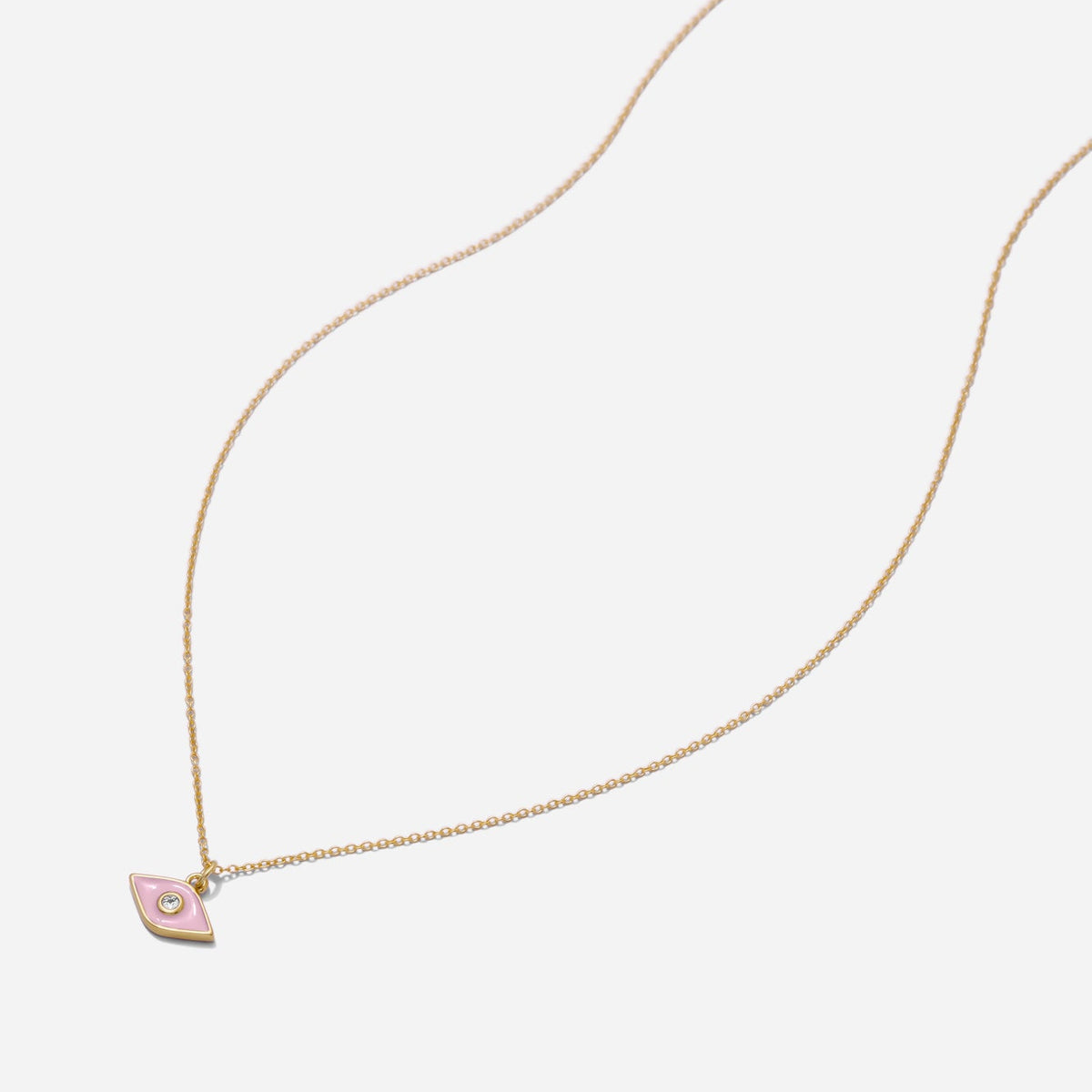 Dainty gold necklace with a small pink evil eye pendant on a light grey background, made by Katie Dean.