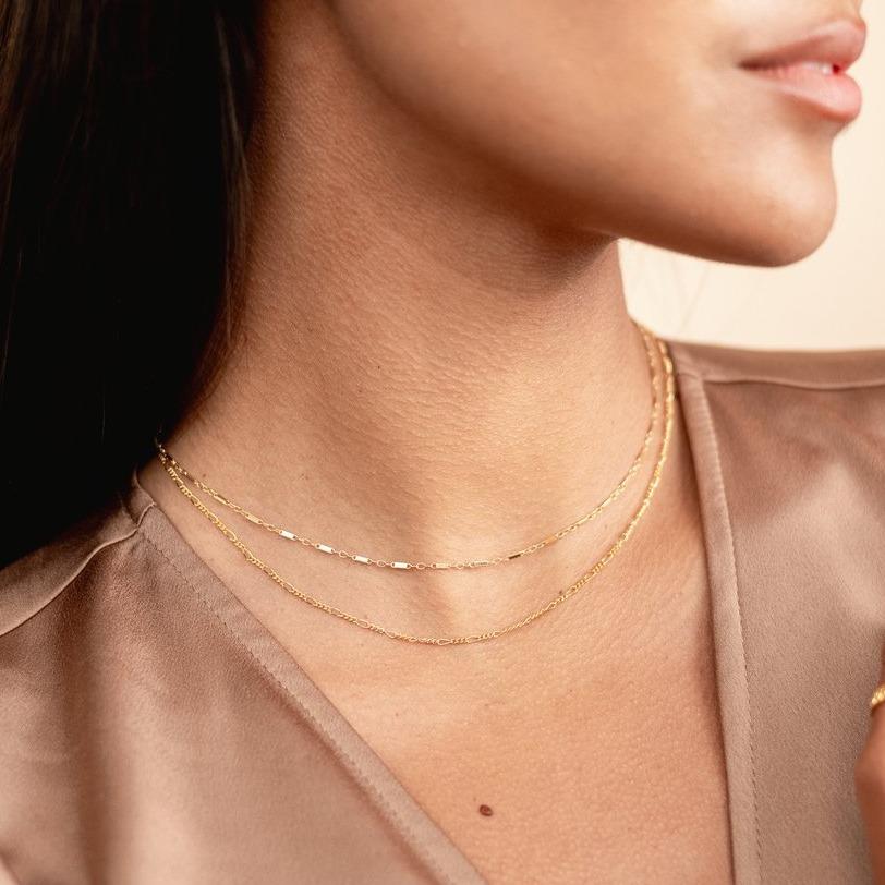 Model wearing brown silk top, looking to the side, wearing the gold Linked Choker and Figaro Chain Choker. Handmade in California by Katie Dean Jewelry.