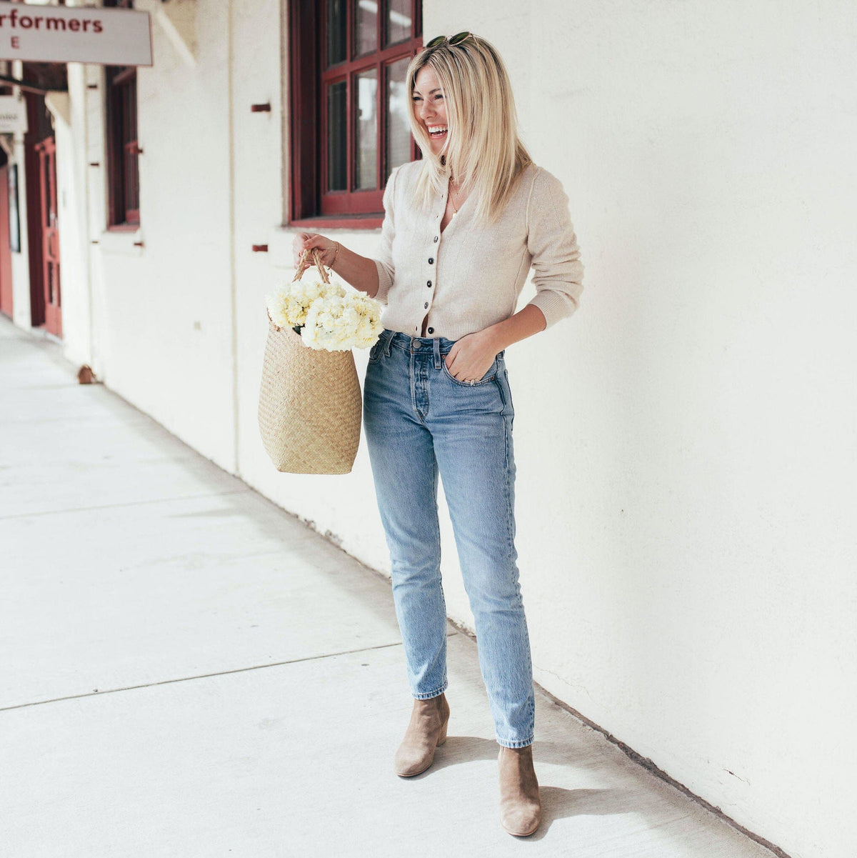Katie Dean, founder of Katie Dean Jewelry carrying a woven bag with flowers in it.