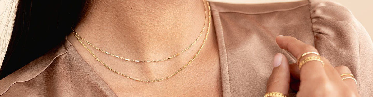 Image showing the upper body of a model wearing dainty gold handmade necklaces and gold rings by Katie Dean Jewelry