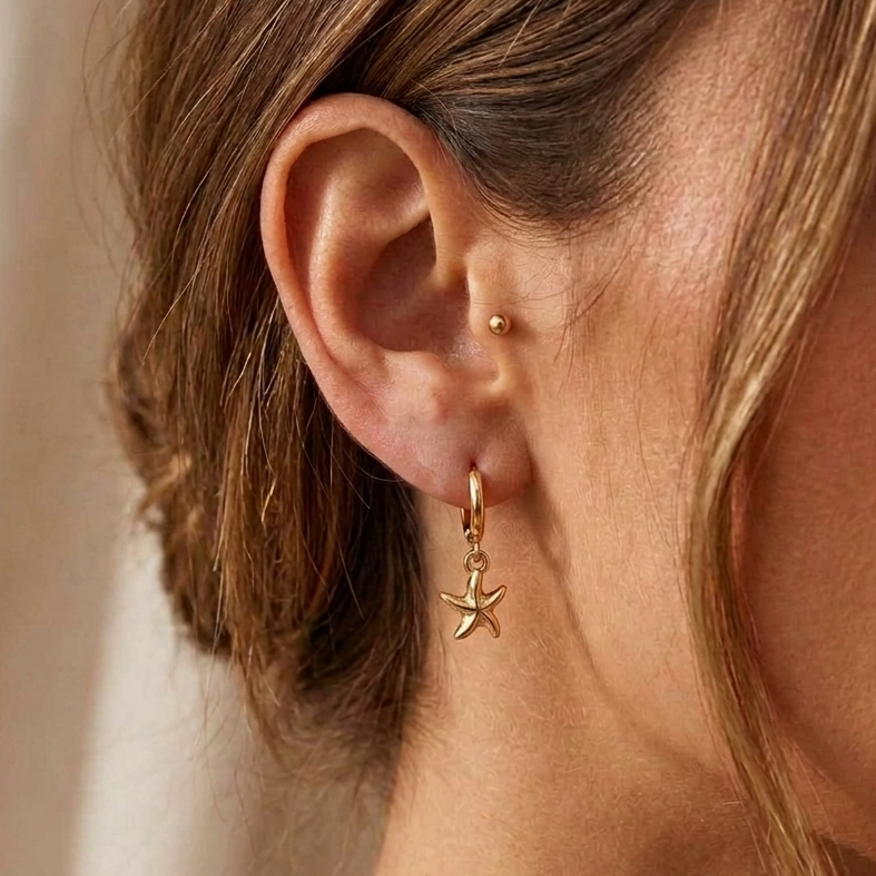 gold hoop earrings with starfish charm pendants on a person
