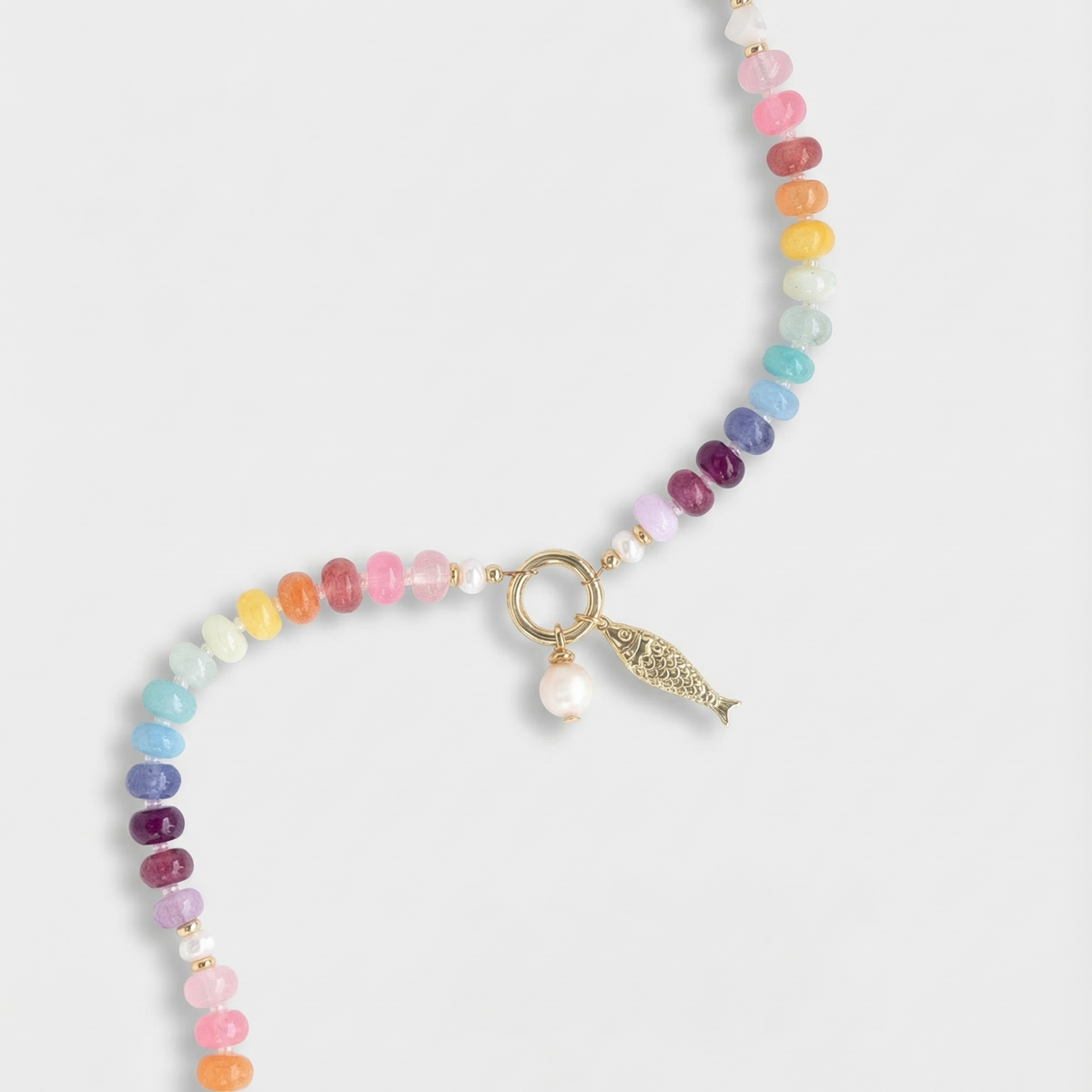Multicolored beaded necklace with a gold fish charm  and a pearl charm on a white background