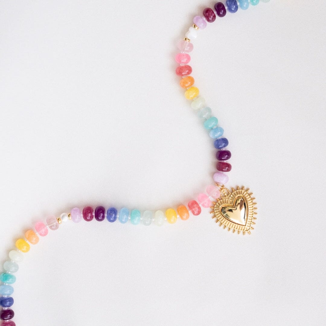 Colorful beaded necklace with a gold heart charm on a white background