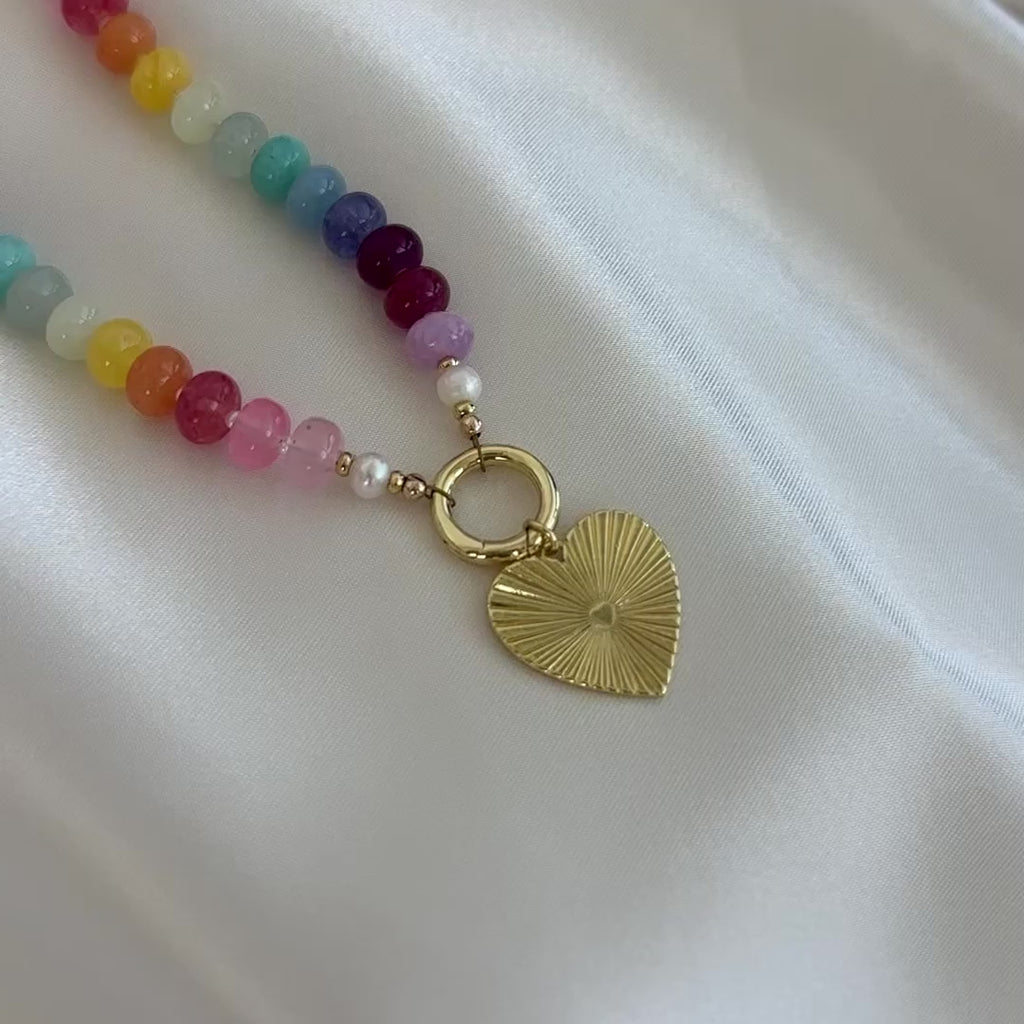 Necklace with colorful beads and a gold clasp with gold heart charm on a white background
