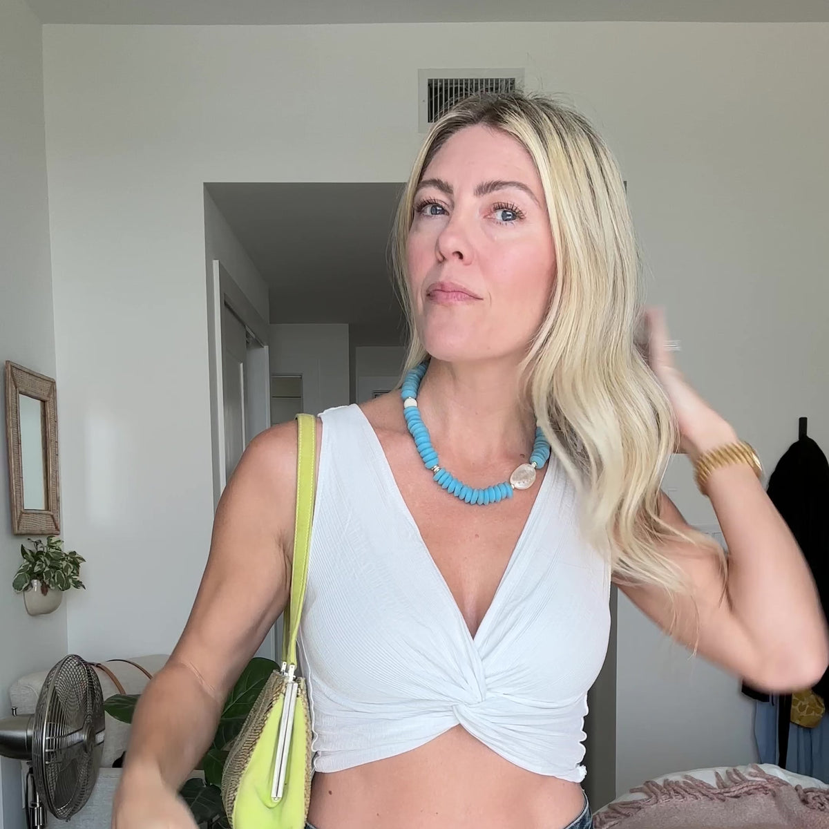 Necklace with blue beads and an abalone shell on a person wearing a white top.