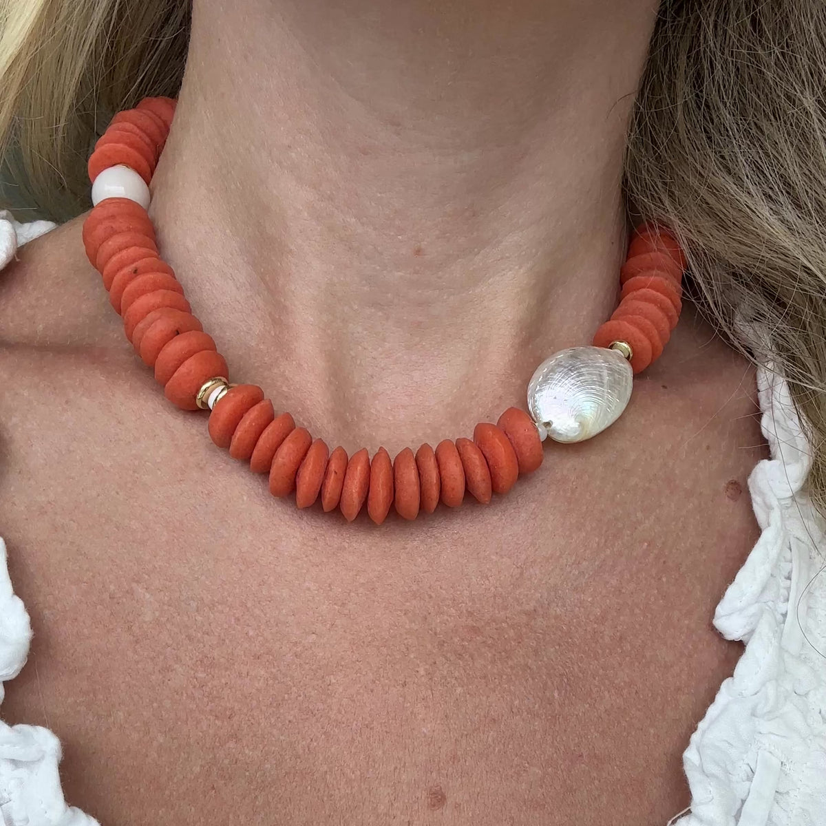 An orange necklace shown on a person.