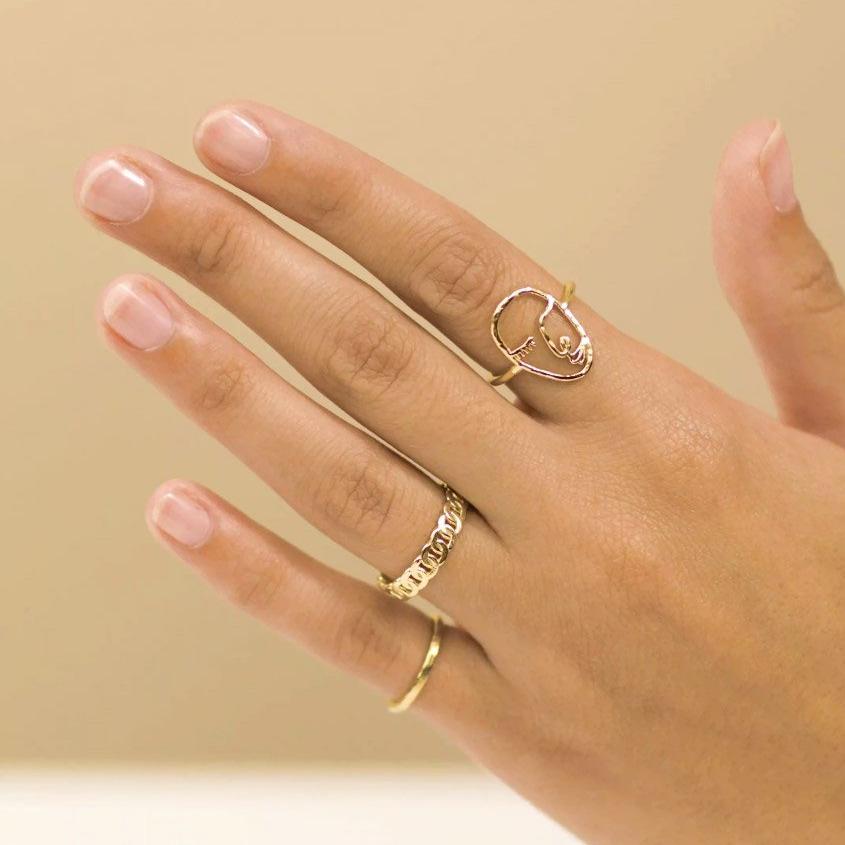 Dainty gold rings handmade by Katie Dean Jewelry, featuring the Artist Face Ring, Figaro Chain Ring and Hammered Band Stacking Ring. 